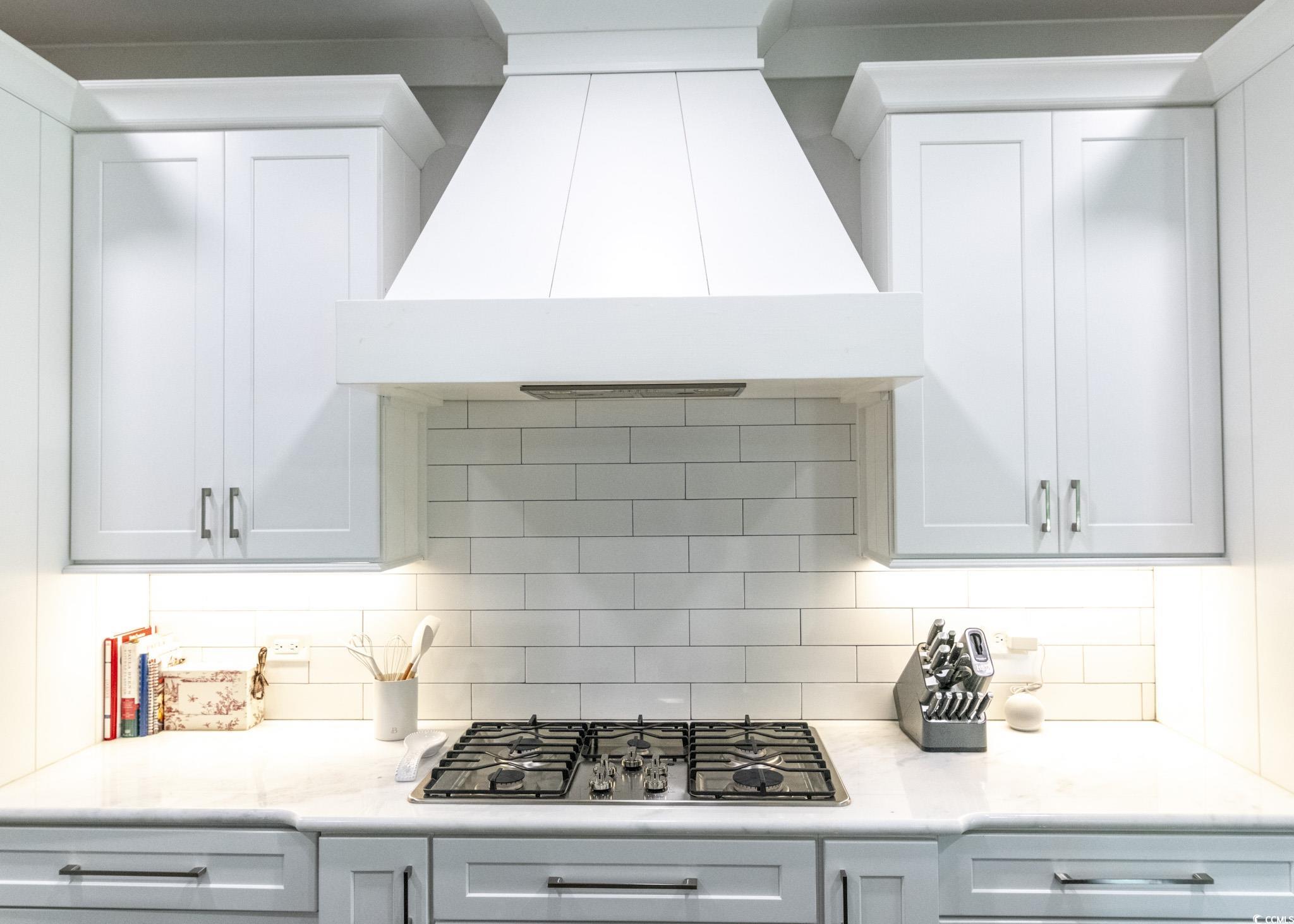 521 Oak Lawn Road Georgetown, SC 29440 - Photo 14 of 40 Kitchen featuring custom range hood, white cabinets, stainless steel gas stovetop, and light stone counters