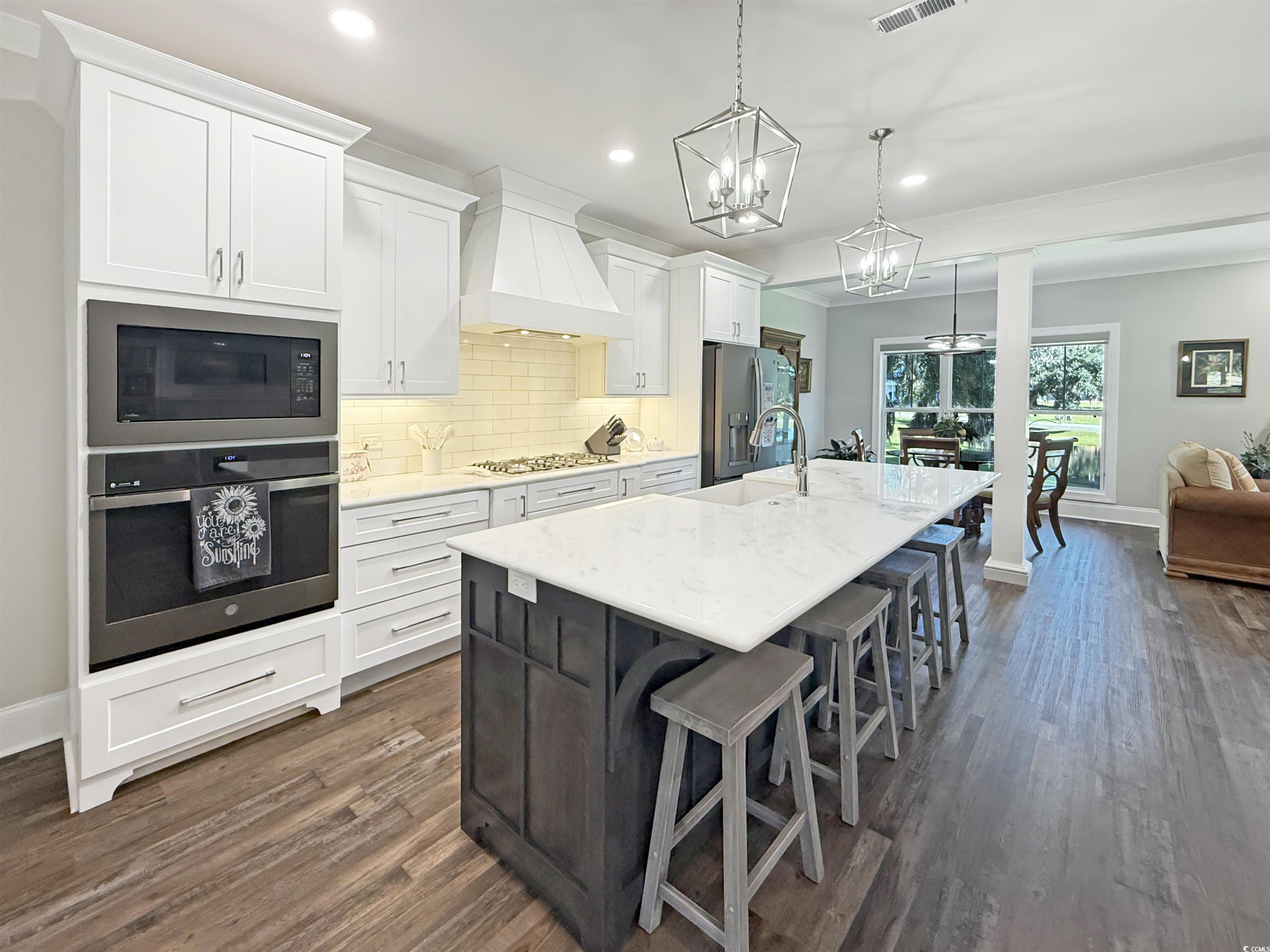 521 Oak Lawn Road Georgetown, SC 29440 - Photo 15 of 40 Kitchen with white cabinetry, stainless steel appliances, a kitchen breakfast bar, a kitchen island with sink, and tasteful backsplash