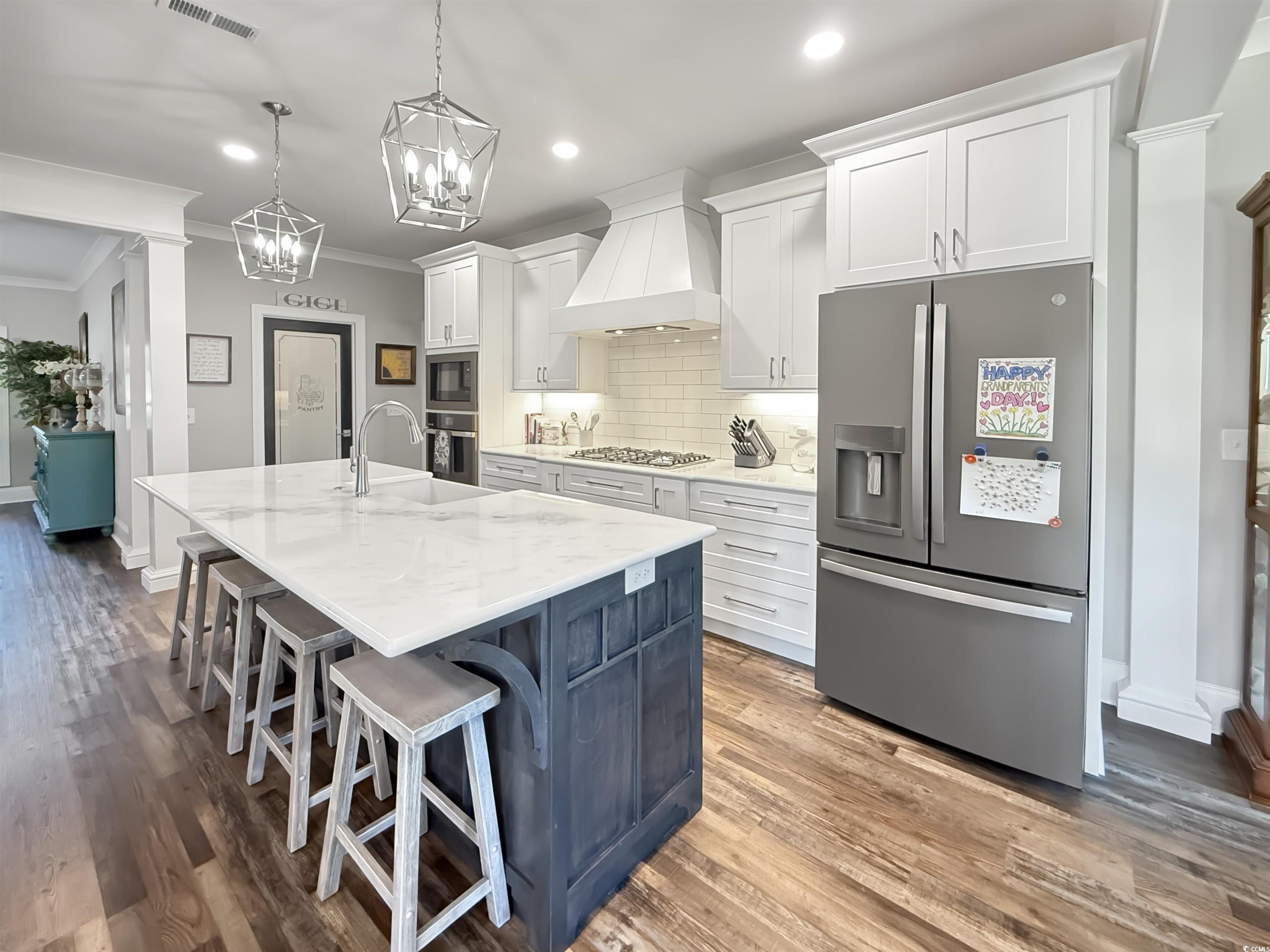 521 Oak Lawn Road Georgetown, SC 29440 - Photo 16 of 40 Kitchen featuring stainless steel appliances, white cabinetry, a breakfast bar, premium range hood, and ornamental molding
