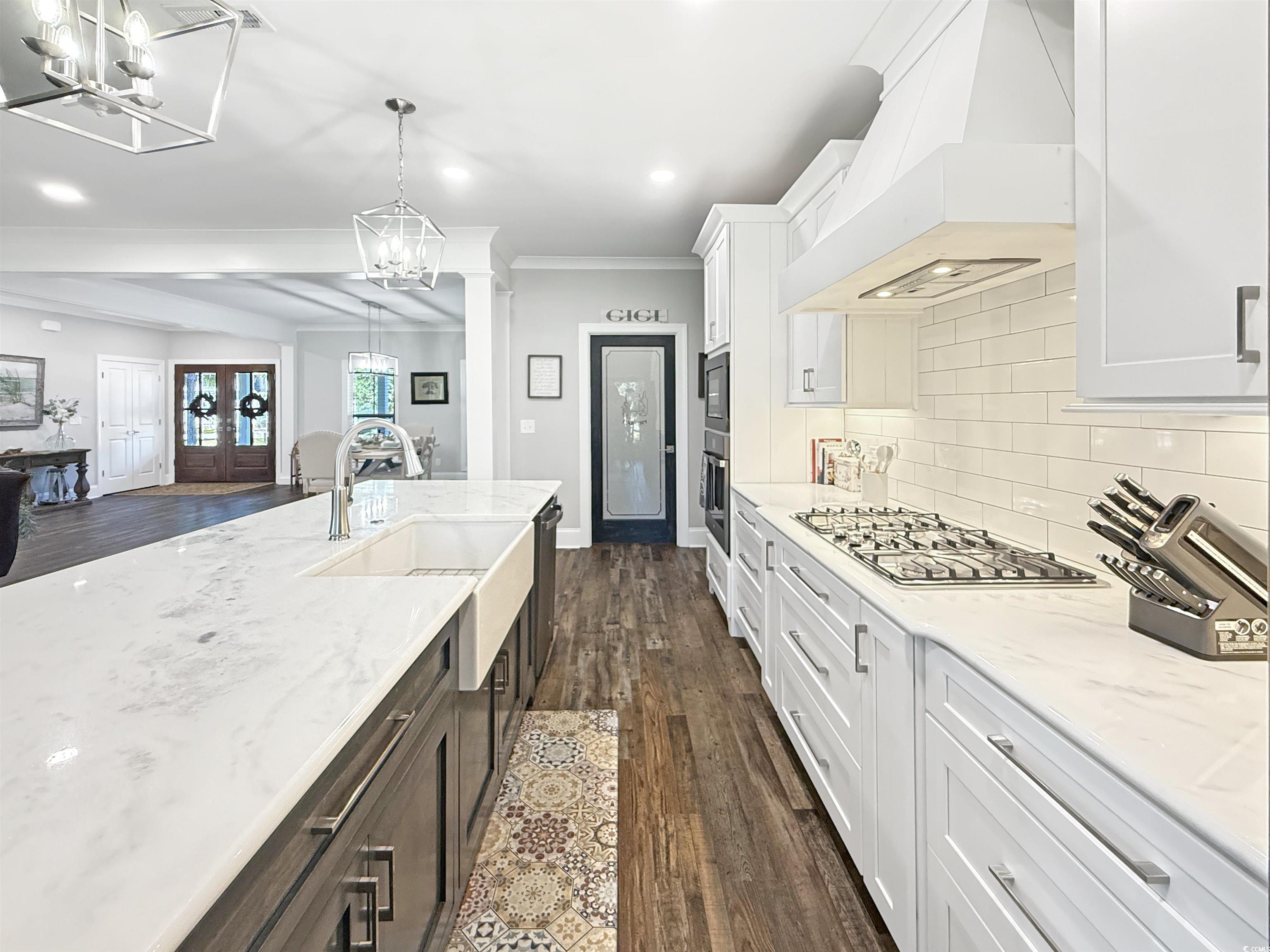 521 Oak Lawn Road Georgetown, SC 29440 - Photo 40 of 40 Kitchen featuring dark wood finished floors, custom range hood, open floor plan, ornamental molding, and white cabinetry