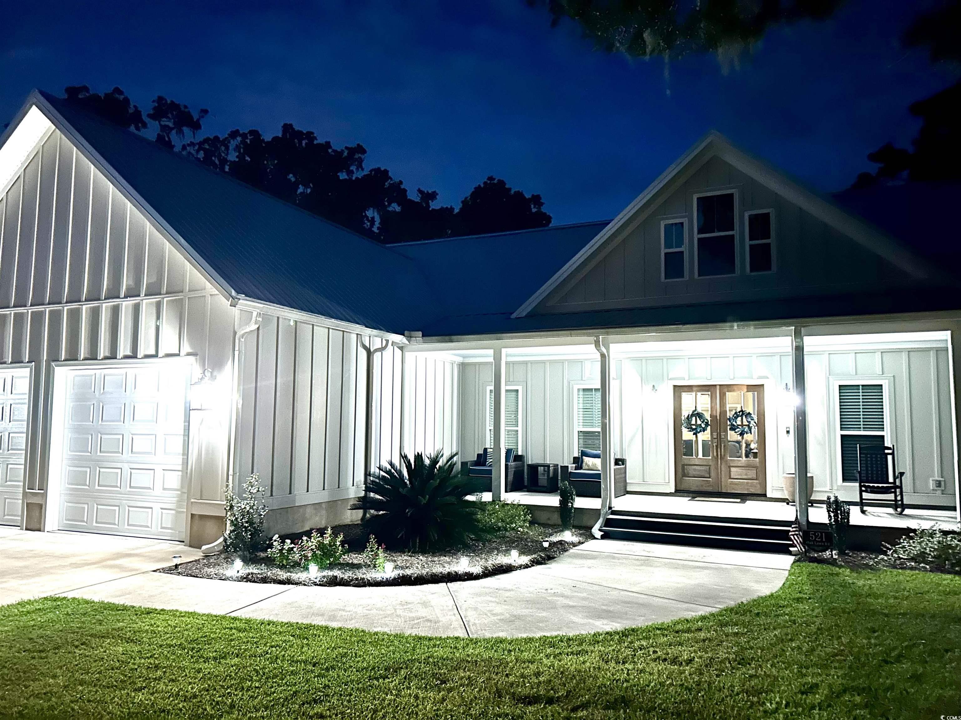 521 Oak Lawn Road Georgetown, SC 29440 - Photo 3 of 40 Property entrance with board and batten siding, covered porch, a lawn, a garage, and a metal roof