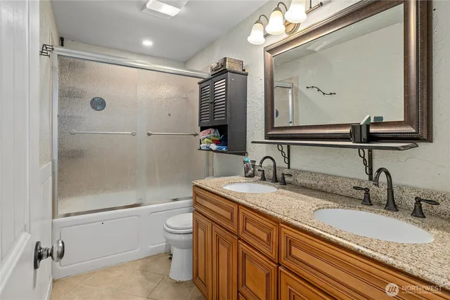 a bathroom with a granite countertop sink a toilet and a mirror