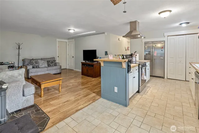a living room with stainless steel appliances kitchen island granite countertop a refrigerator a stove top oven a sink with island and chairs