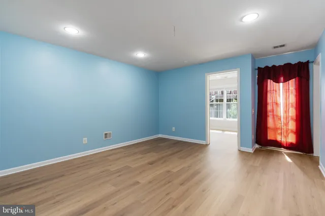 an empty room with wooden floor and windows