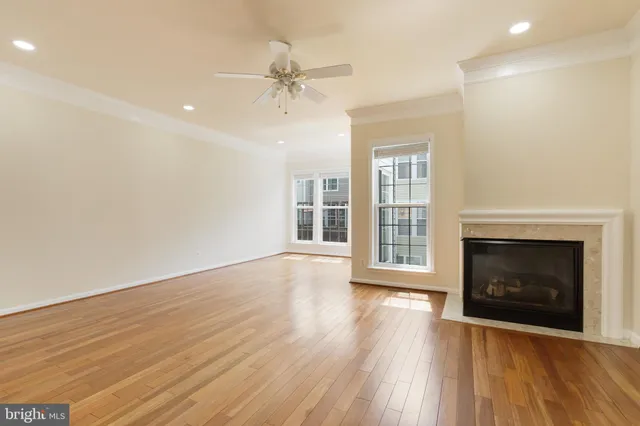a view of an empty room with wooden floor fireplace and a window