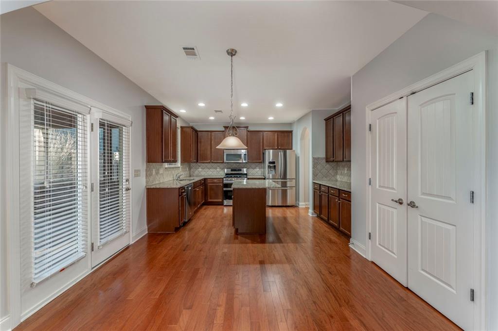 624 East Hampton Place Canton, GA 30115 - Photo 12 of 37 a large kitchen with a center island wooden floor stainless steel appliances and a window