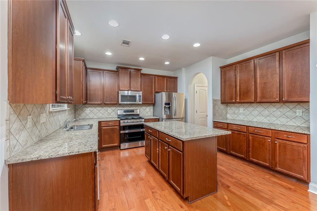 624 East Hampton Place Canton, GA 30115 - Photo 15 of 37 a kitchen with stainless steel appliances granite countertop wooden cabinets a sink dishwasher a stove and a refrigerator with wooden floor