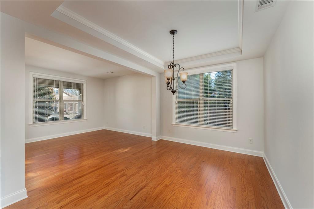 624 East Hampton Place Canton, GA 30115 - Photo 8 of 37 an empty room with wooden floor chandelier and windows