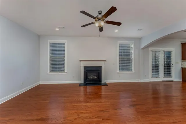 a view of an empty room with wooden floor fireplace and a window