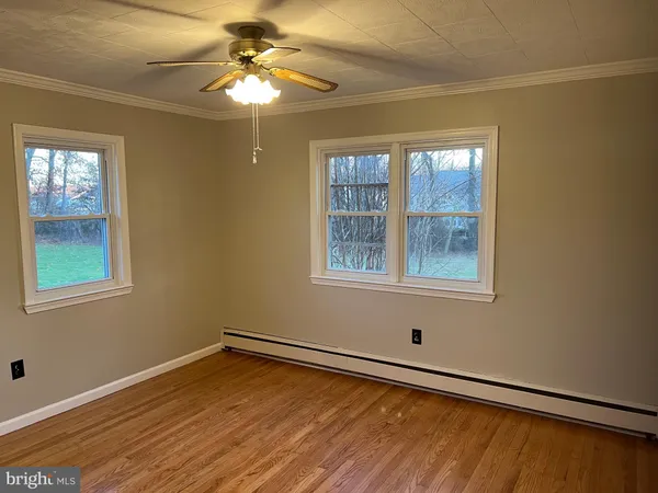 a view of an empty room with window and chandelier fan