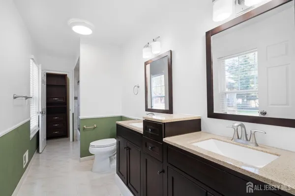 a bathroom with a double vanity sink toilet and a tub