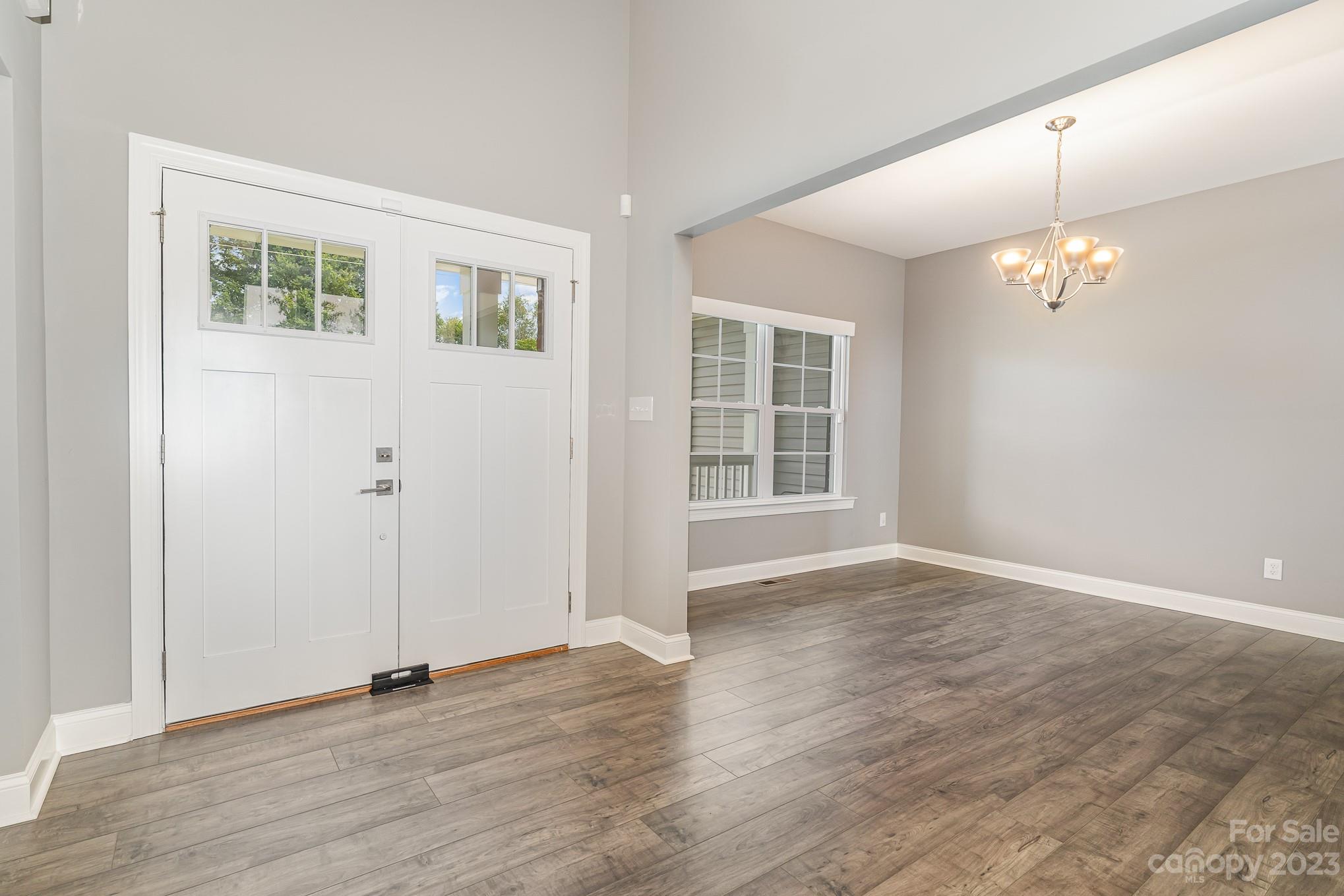 556 Sain Road Mocksville, NC 27028 - Photo 11 of 48 an empty room with wooden floor chandelier and windows