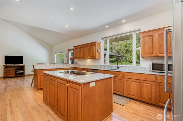 a kitchen with stainless steel appliances granite countertop wooden floor sink stove and a granite counter top