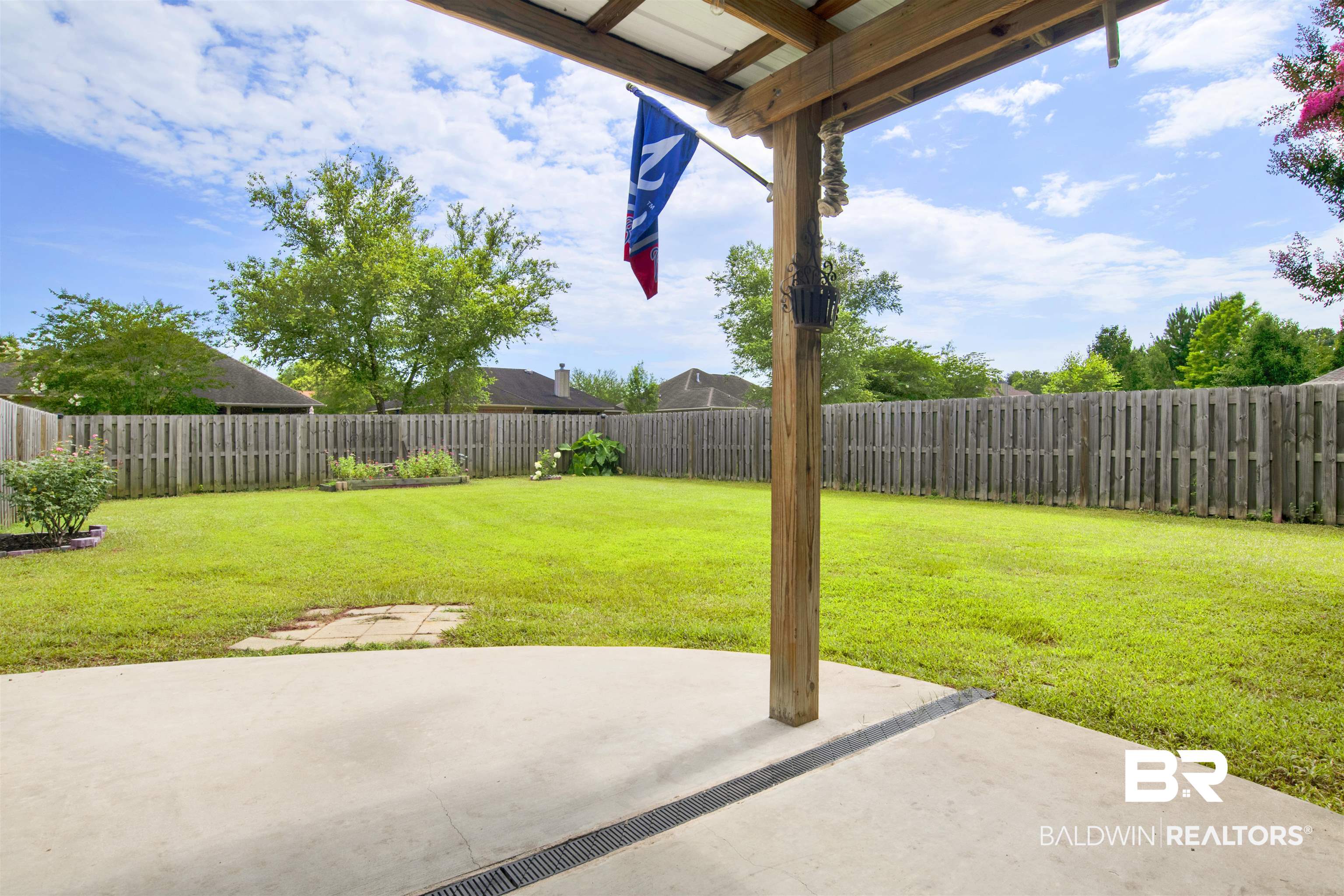 10368 Gayfer Rd Extension Fairhope, AL 36532 - Photo 34 of 43 Spacious backyard featuring a concrete patio with an overhead wooden structure, a full privacy fence, and a large manicured lawn
