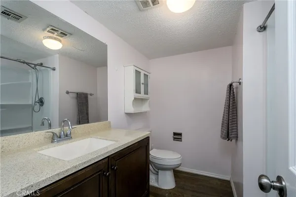 a bathroom with a granite countertop sink a toilet and mirror