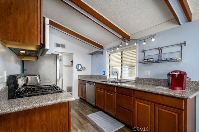a kitchen with granite countertop a sink stainless steel appliances and cabinets