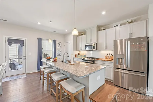 a kitchen with a refrigerator a stove top oven a dining table and chairs with wooden floor