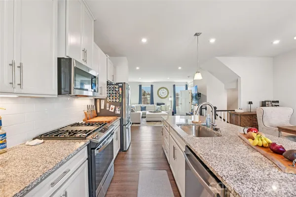 a kitchen with stainless steel appliances granite countertop a stove top oven a sink a counter space and cabinets