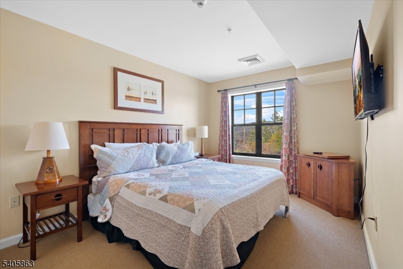 200 Highway 94, Unit 249 Vernon, NJ 07462 - Photo 21 of 28 a bedroom with a bed and a flat tv screen on a dresser