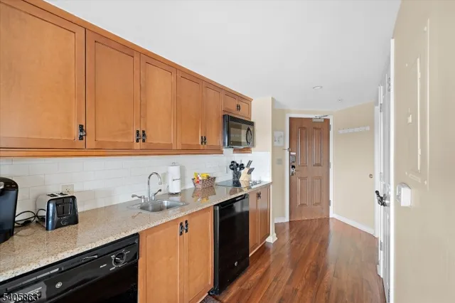 a kitchen with granite countertop wooden cabinets a sink and dishwasher