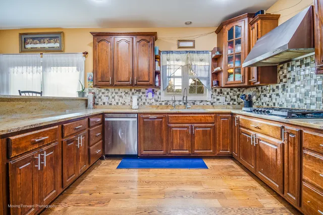 a kitchen with stainless steel appliances granite countertop a stove a sink dishwasher and cabinets with wooden floor