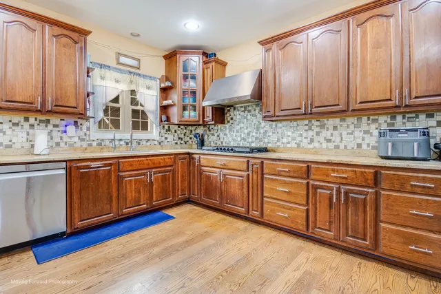 a kitchen with stainless steel appliances granite countertop wooden cabinets a sink and dishwasher with wooden floor