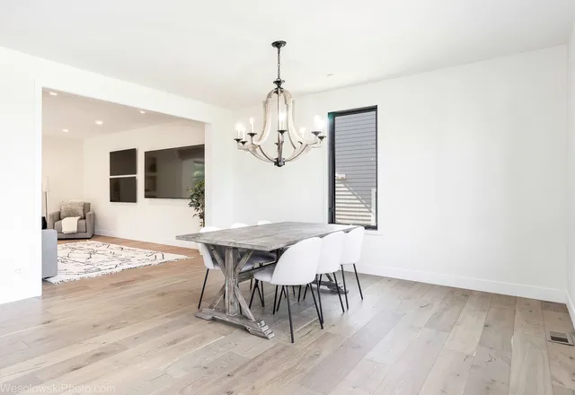 a dining room with wooden floor a chandelier a wooden table and chairs