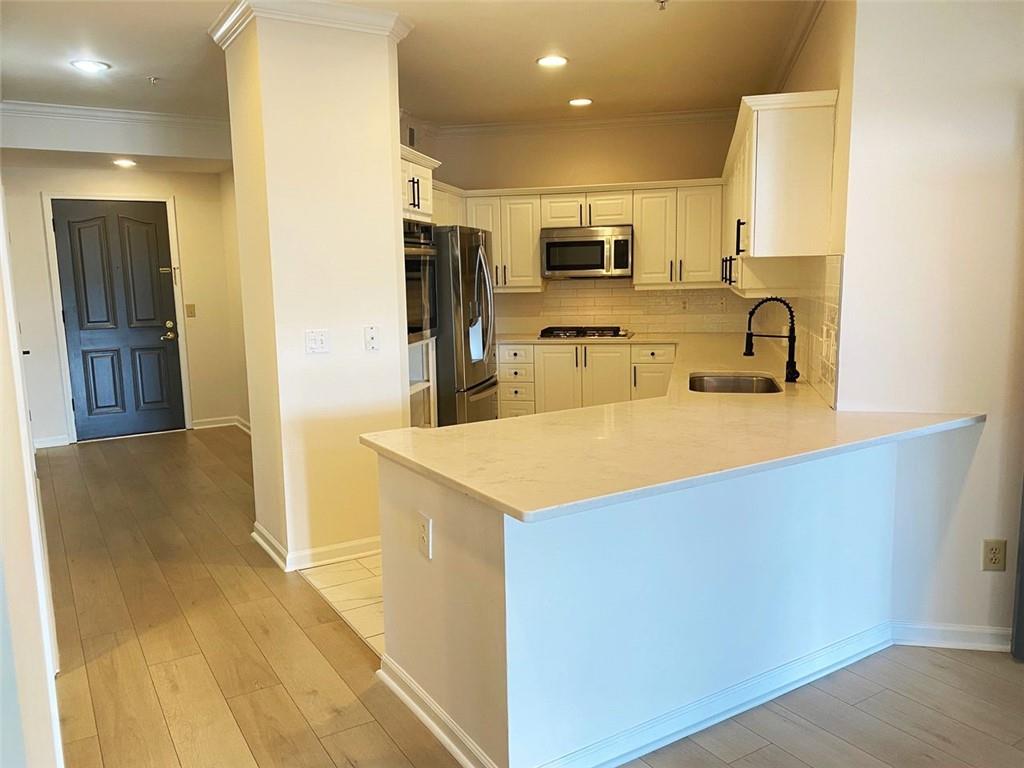 3047 Lenox Road Northeast, Unit 1202 Atlanta, GA 30324 - Photo 10 of 69 a kitchen with stainless steel appliances a sink a stove a refrigerator cabinets and a dining table