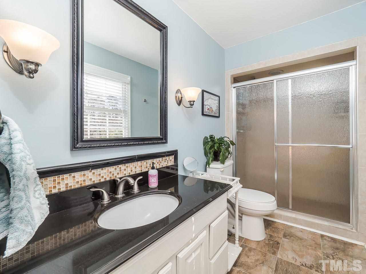 2002 Port Royal Road Raleigh, NC 27609 - Photo 20 of 23 a bathroom with a granite countertop sink toilet a mirror and shower