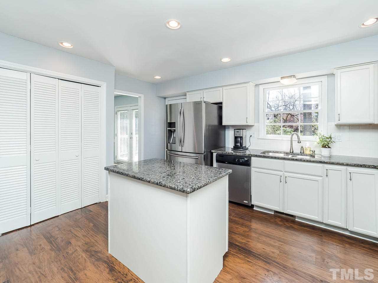 2002 Port Royal Road Raleigh, NC 27609 - Photo 5 of 23 a kitchen with stainless steel appliances granite countertop a stove a sink and white cabinets with wooden floor