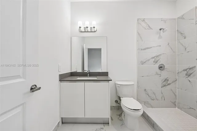 a bathroom with a granite countertop sink a toilet and shower