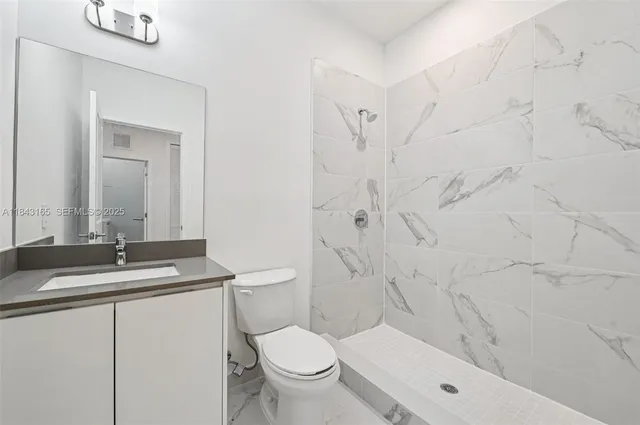 a bathroom with a granite countertop sink toilet mirror and shower