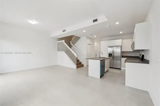 a view of kitchen with refrigerator and white cabinets