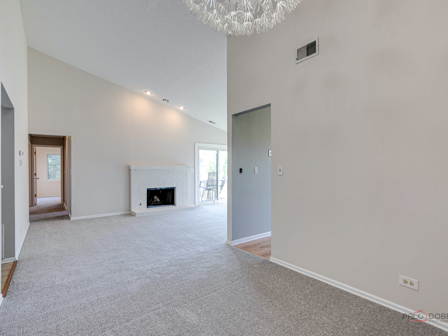 1082 Pine Tree Circle North, Unit 1082 Buffalo Grove, IL 60089 - Photo 10 of 26 an empty room with a fireplace and a chandelier fan