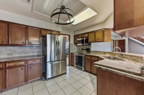 a kitchen with stainless steel appliances granite countertop a sink refrigerator stove and microwave