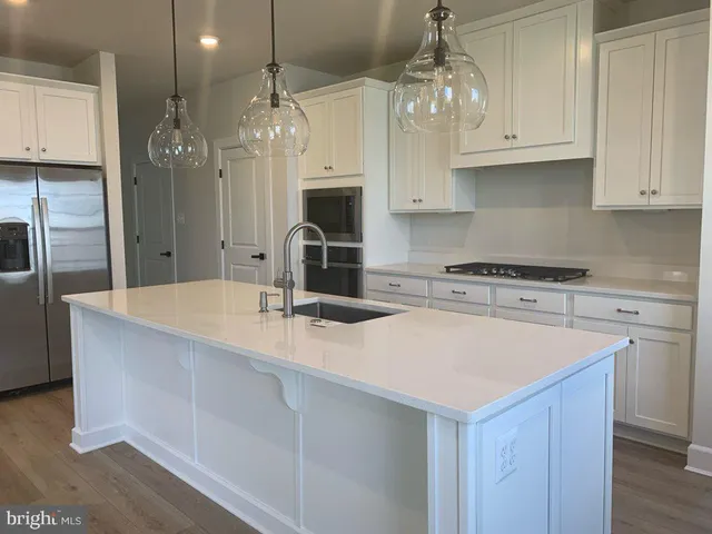 a kitchen with kitchen island granite countertop a sink cabinets and stainless steel appliances