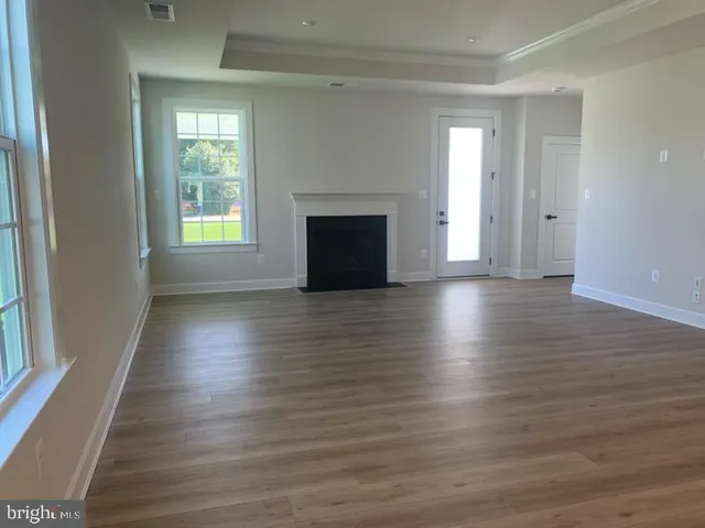 an empty room with wooden floor fireplace and windows