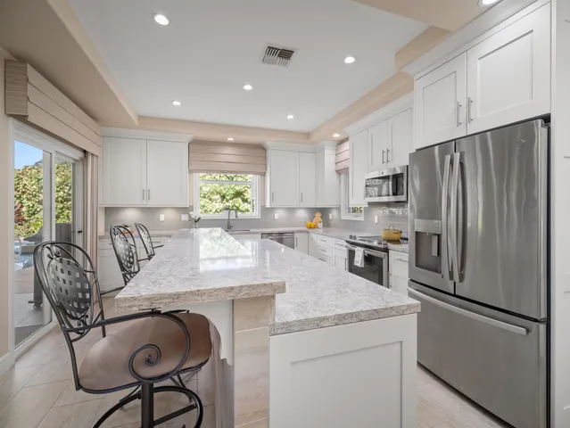 a kitchen with granite countertop a refrigerator a stove a dining table and chairs