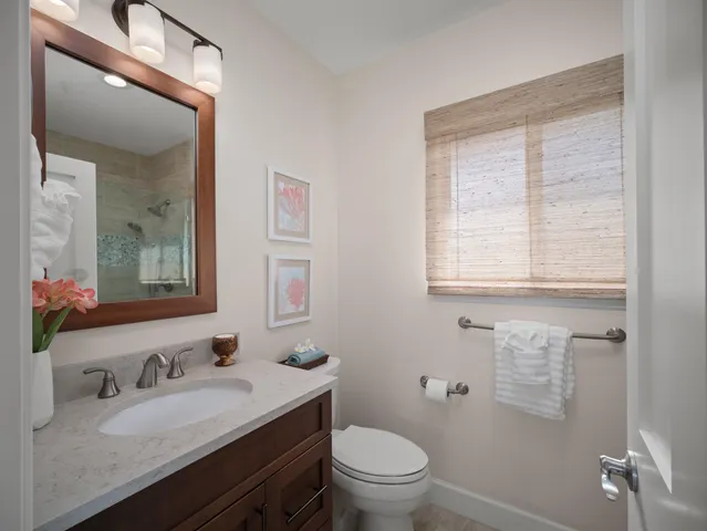 a bathroom with a granite countertop toilet a sink a mirror and a window