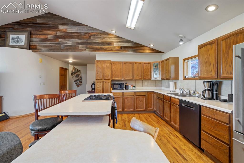 2550 Slocum Road Peyton, CO 80831 - Photo 27 of 50 Spacious kitchen featuring wood-finish flooring, a large island with an integrated cooktop, and abundant wood cabinetry
