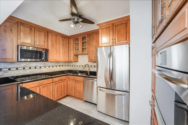 a kitchen with stainless steel appliances granite countertop a refrigerator a stove a sink dishwasher and white cabinets with wooden floor