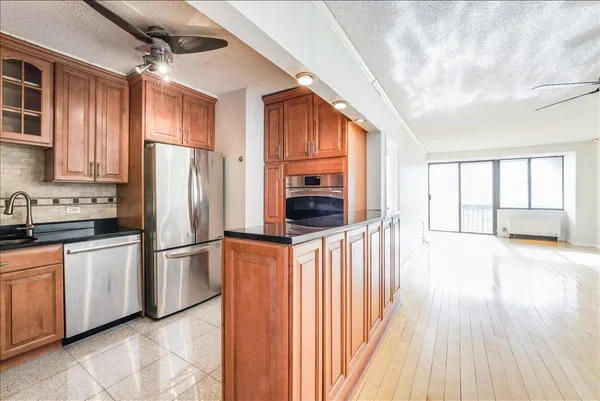a kitchen with stainless steel appliances granite countertop a refrigerator a sink dishwasher a stove and a refrigerator with wooden floor