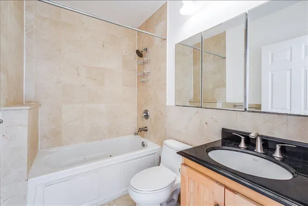 a bathroom with a granite countertop sink a toilet a mirror and shower