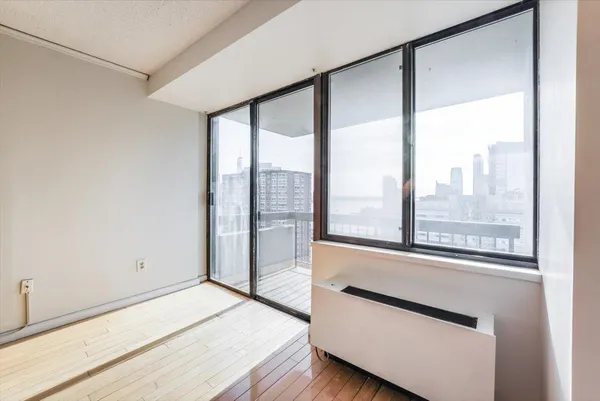a view of an empty room with wooden floor and a window