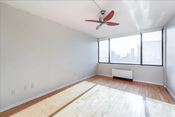 an empty room with windows and ceiling fan