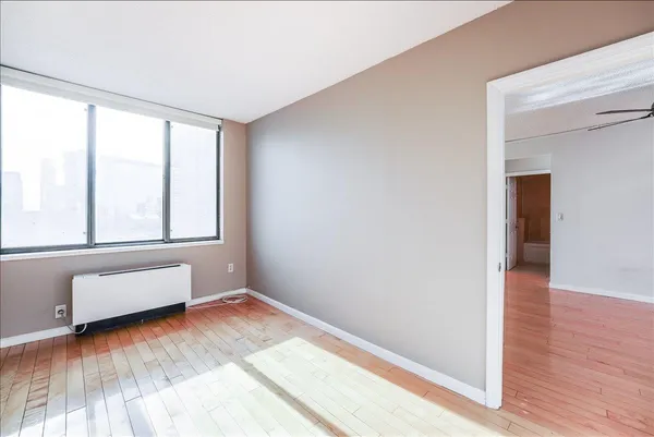 an empty room with wooden floor and windows