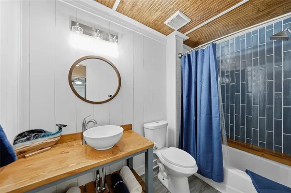 a bathroom with a sink a toilet a mirror and shower curtain