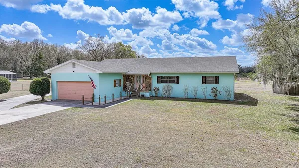 a view of house with yard and trees in the background
