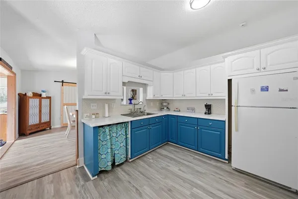 a kitchen with stainless steel appliances granite countertop a refrigerator a stove a sink and white cabinets with wooden floor