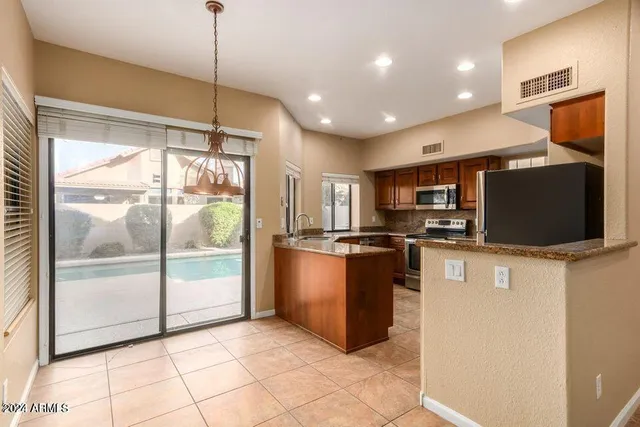 a kitchen with stainless steel appliances granite countertop a refrigerator a sink a stove top oven a counter space and cabinets